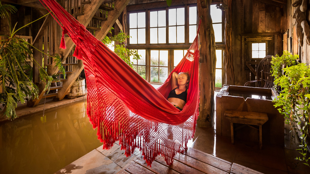 Guest hanging in a red hammock above indoor hot springs.