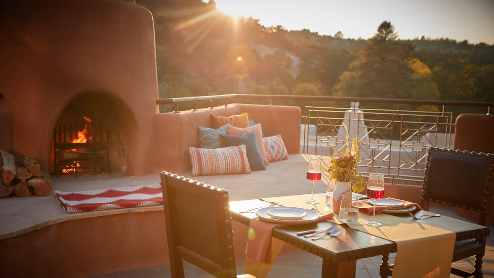 Bishop's Lodge dining area with a traditional adobe fireplace and table set up for two with full wine glasses. 