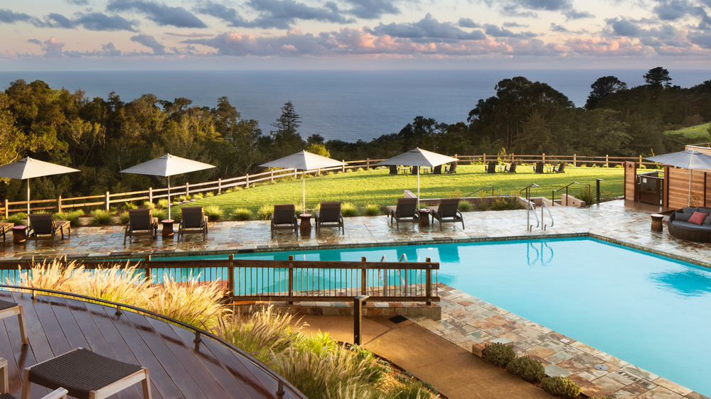 Ventana Big Sur pool area with lounge options set in front of a large panoramic view of the ocean. 