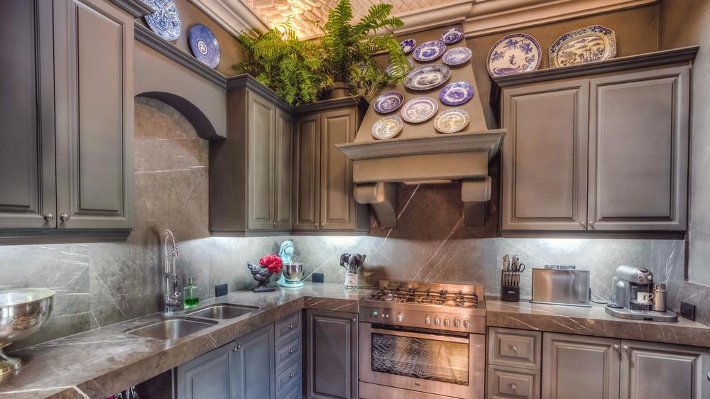 Luxury modern kitchen with grey cabinets with decorative antique plates and stainless steel appliances. 