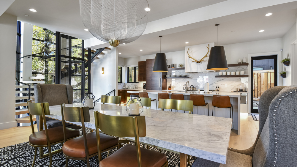 Modern luxury kitchen with leather and brass accents with a spiral staircase and large wooden and island with deer antlers above sink.