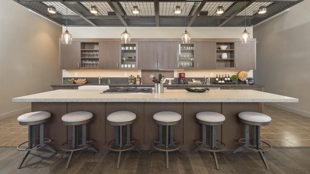 Modern luxury kitchen with large island and light fixtures hanging from a metal roof. 