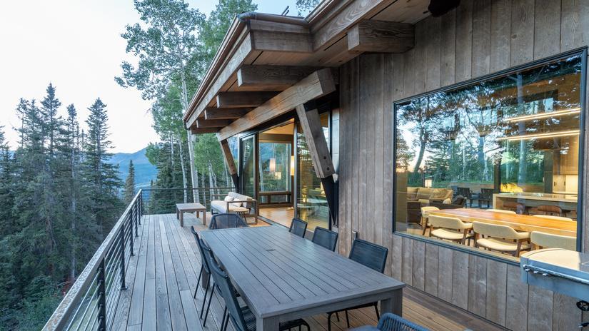 Outdoor dining area of Marmot Ridge, an Inspirato home in Telluride, surrounded by trees and mountain views.