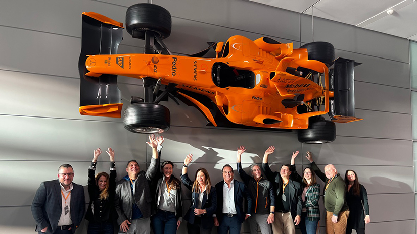 Inspirato members standing beneath a F1 car mounted on a wall