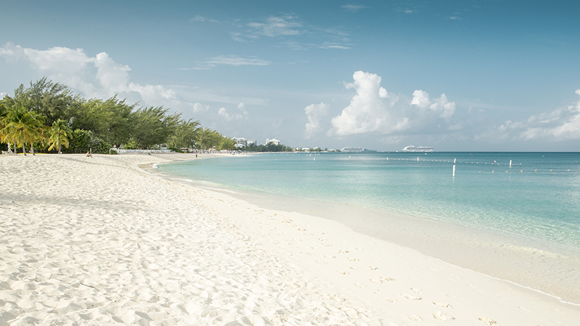 Clear blue turquoise waters and white sand beach at Seven Mile Beach in Grand Cayman.