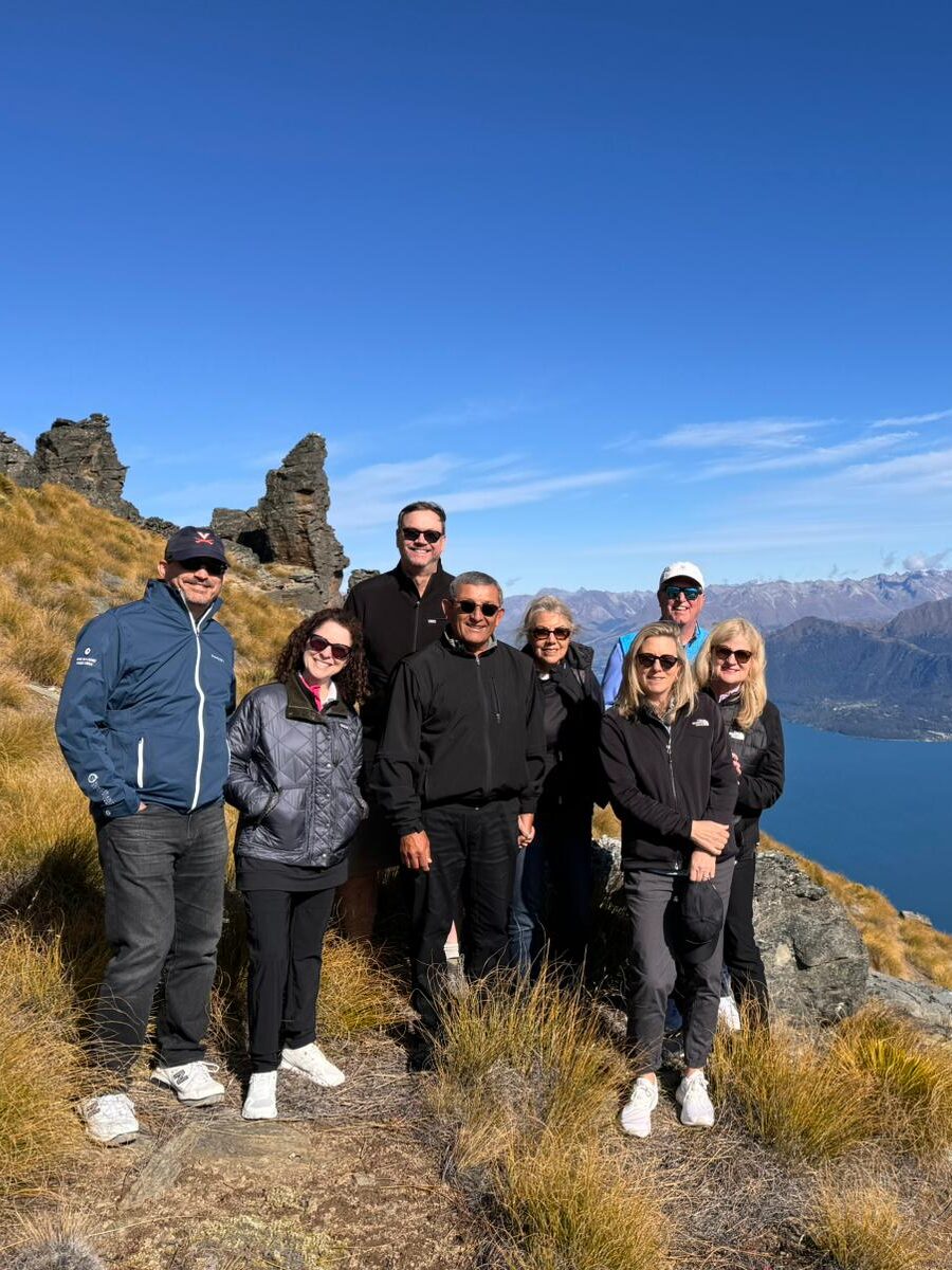 Inspirato members group photos with a New Zealand mountain and lake vista behind them