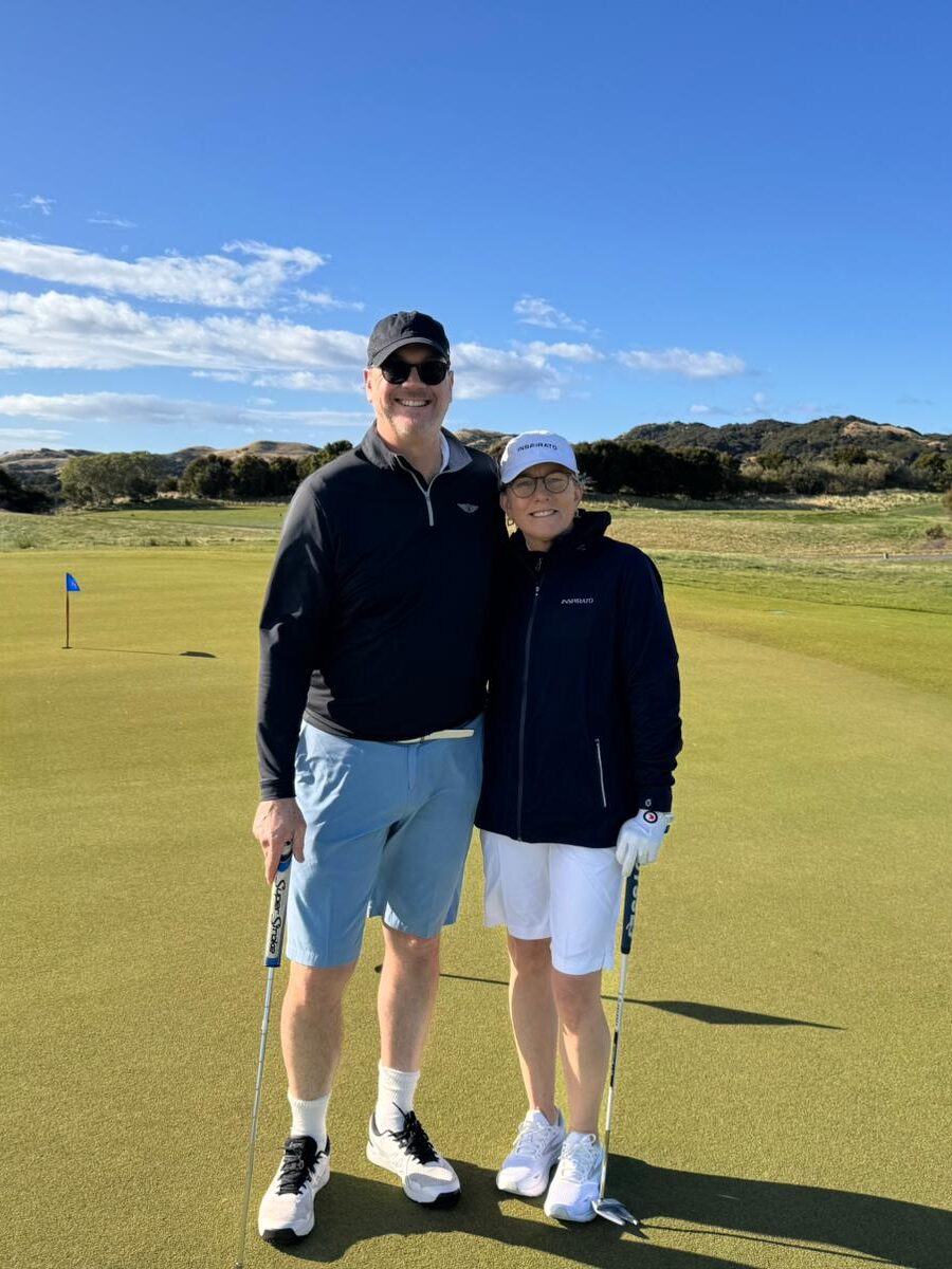 Two Inspirato members embracing for a photo on a golf green