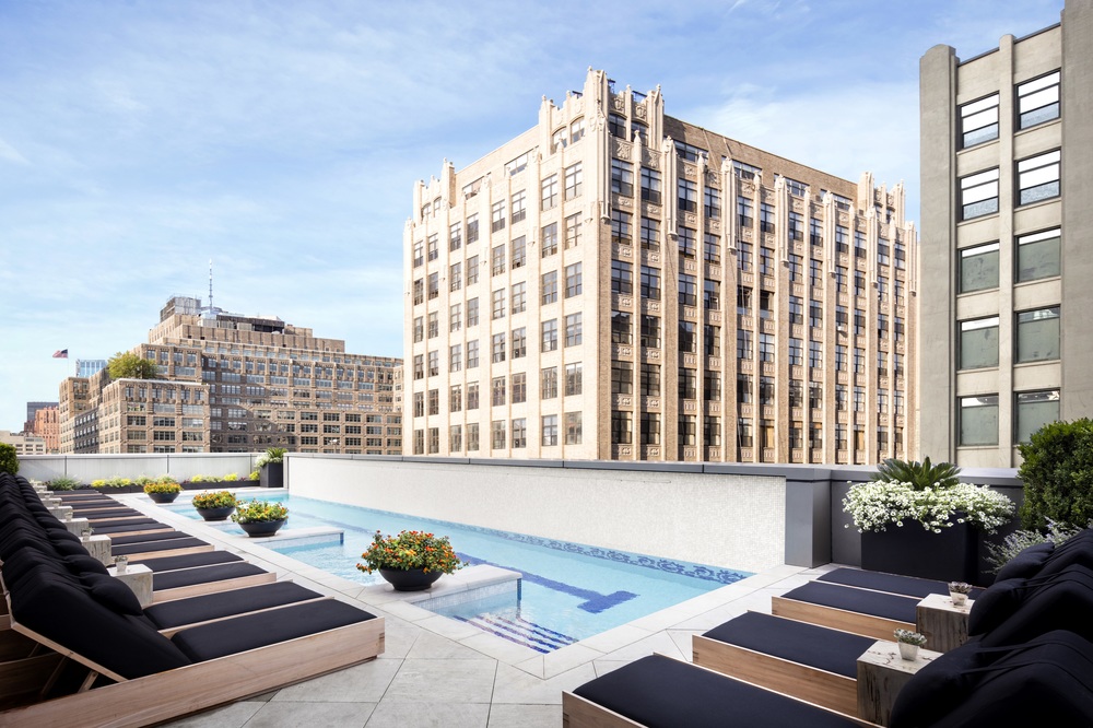 Inspirato SoHo at The Dominick pool area with rectangular pool, poolside lounge chairs, and views of the surrounding skyscrapers