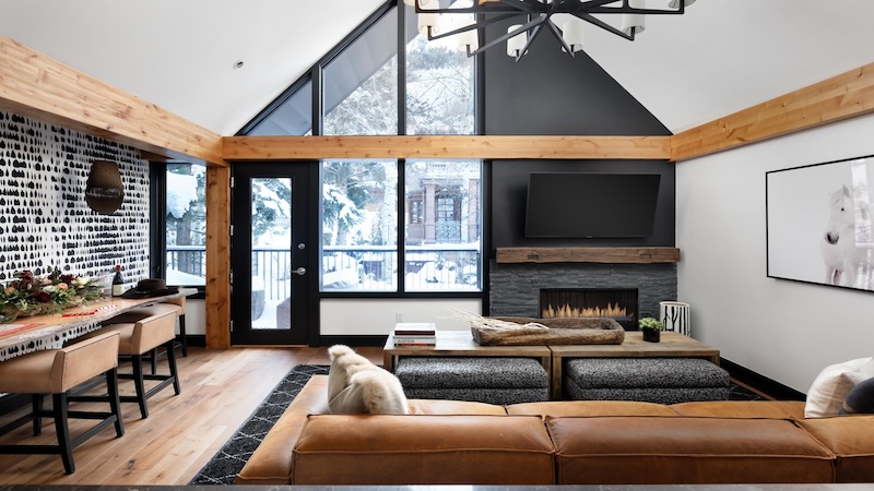 Cooper Gulch living area with vaulted ceiling and black and wooden accents through out the home with furniture arranged in front of a fireplace.