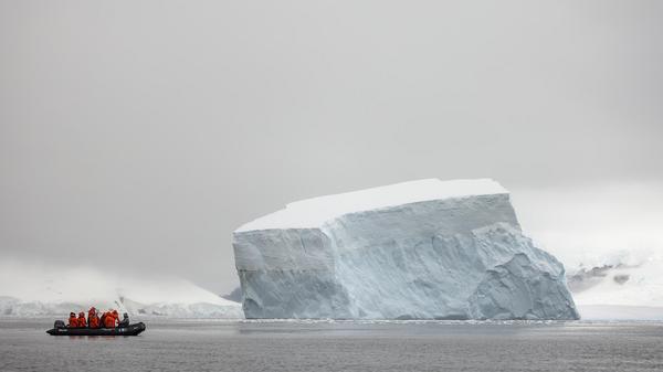 Inspirato members in a zodiac boat looking at sky scraping icebergs in the ocean