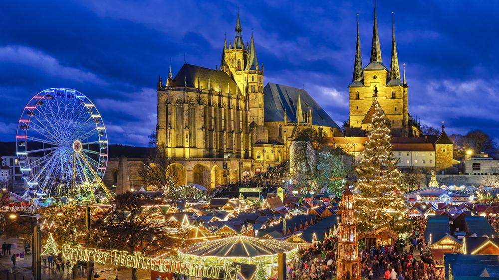 View of a illuminated Christmas market in Germany with a ferris wheel and cathedral with lots of spires