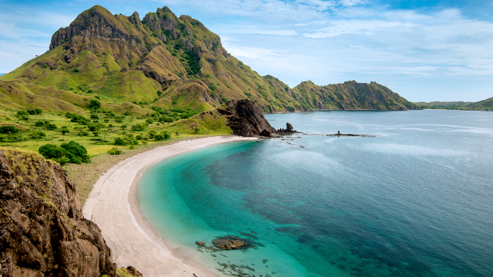 Views of a bay with towering green mountains with turquoise colored water