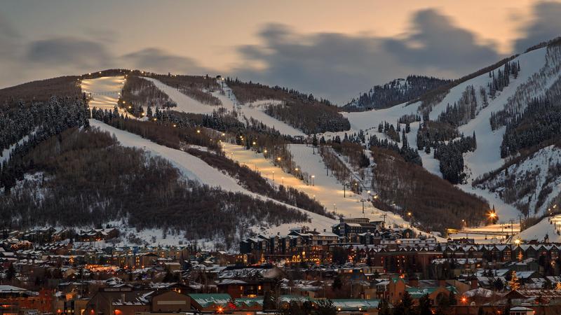 Park City resort and mountain slopes during dusk with the town of Park City at the base.