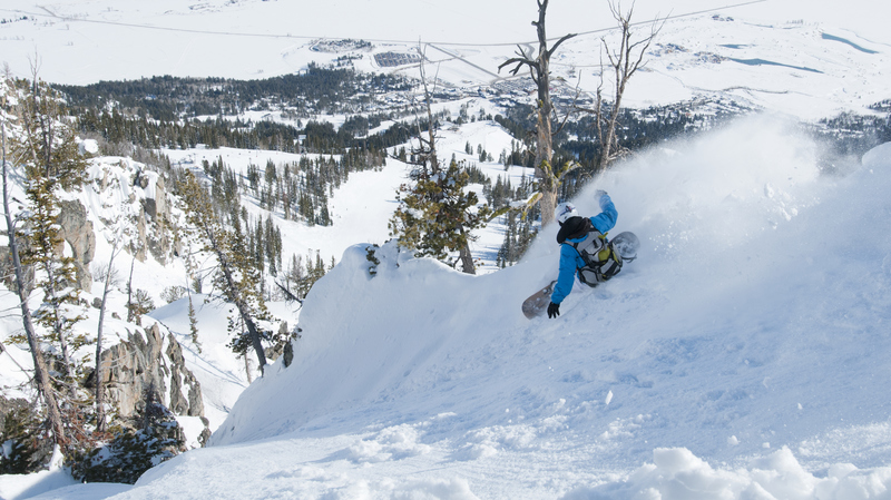 A snowboarder riding down a couloir on Jackson Hole resort. 