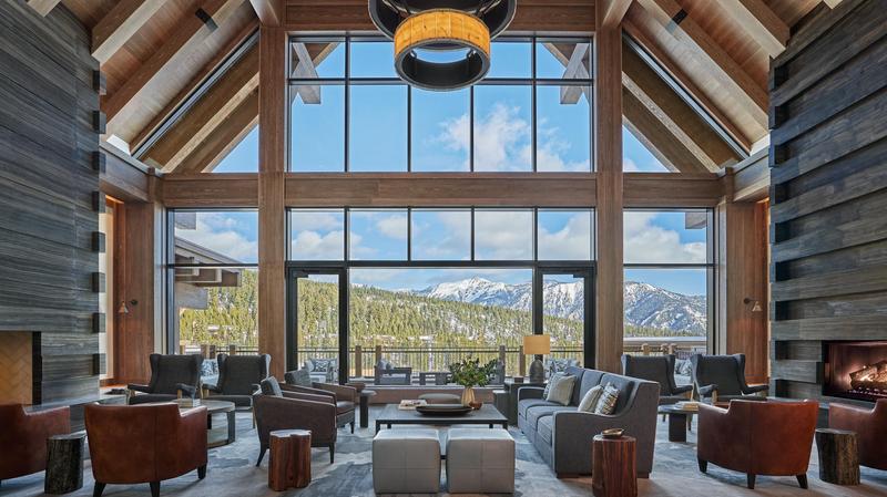 Montage Big Sky lobby with high ceilings with lots of leather furniture arranged in circles with floor to ceiling window with views of nearby mountains. 