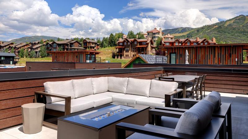 Howler rooftop patio with furniture arrange around a table with fire pit in the center with views of Steamboat resort and other homes at the base of the mountain