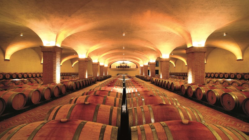 A large dimly lit wine cellar with many barrels of wine