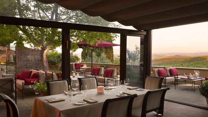 Rosewood Castiglion del Bosco outdoor dining area during sunset with red accents and full set up dining tables