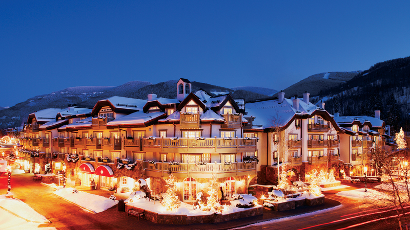 Exterior of Sonnenalp Hotel at night with streaking of light from the traffic in front of the entrance awnings. 