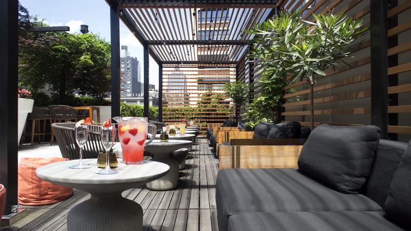 Outdoor cabanas with pitchers of cocktails with fresh fruit and the surrounding skyline of New York City.