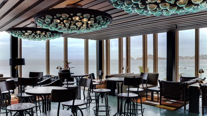 Indoor dining area with modern light fixtures grouped into the ceiling and unobstructed ocean views.