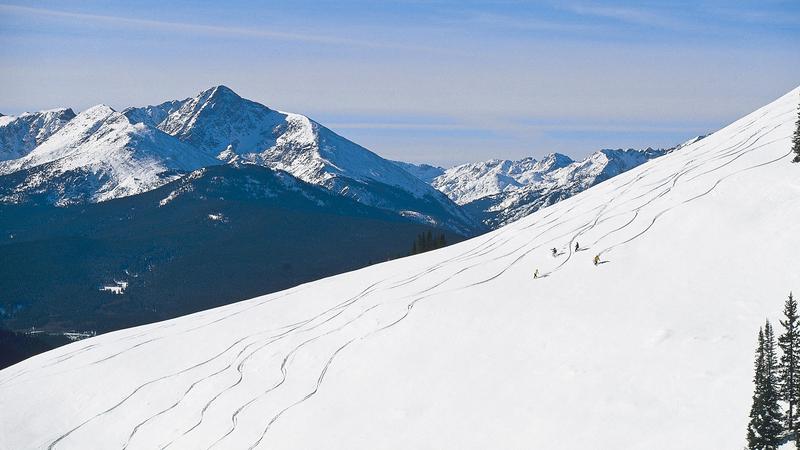 Ski slope with fresh snow and tracks from skier and snowboarders riding down the mountain. 