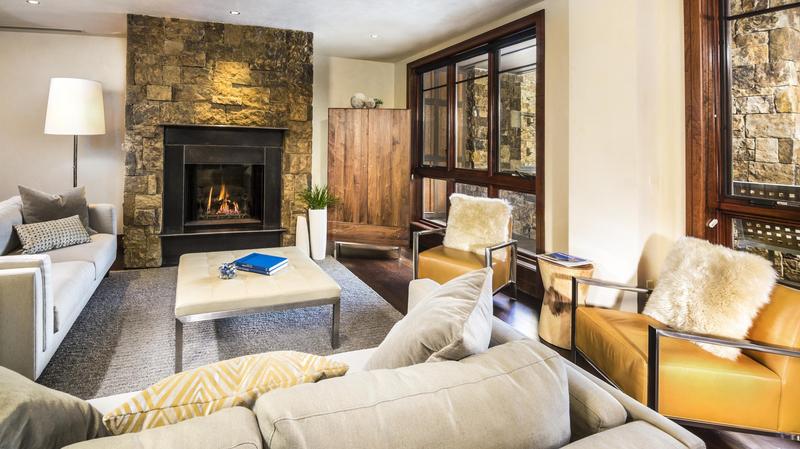 Living room of Prima unit at the Solaris Hotel with a stone fireplace and furniture arranged around a coffee table. 