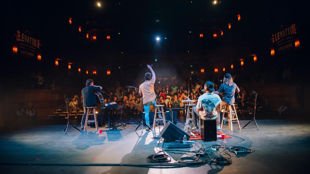 Musicians on an stage with colorful stage lights.