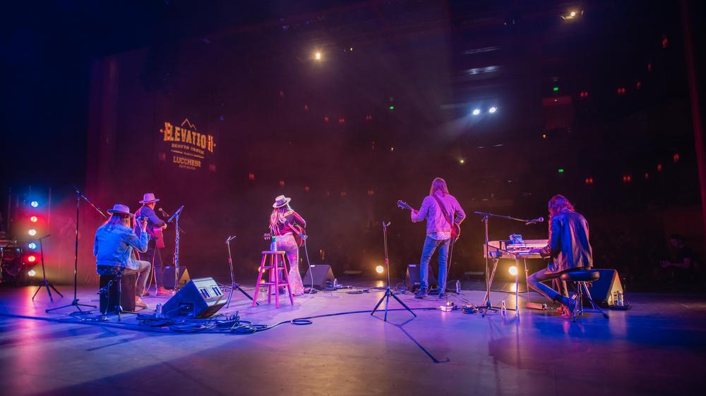 Musicians on an stage with colorful stage lights.