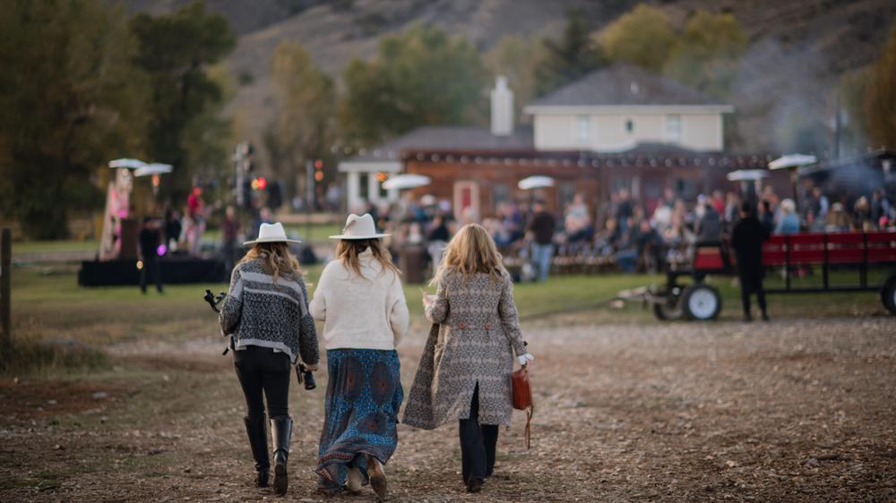 Three women walking back towards the outdoor Elevation Beaver Creek music festival set up. 