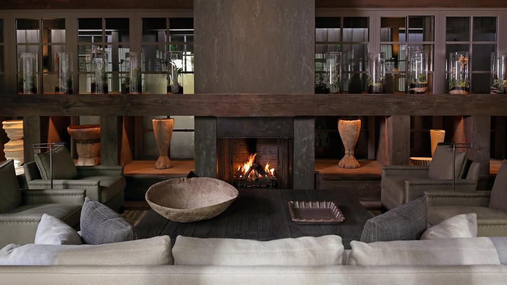 Moody lobby with lots of wood accents with a fireplace with furniture arranged around it with lots of clay pottery decor.