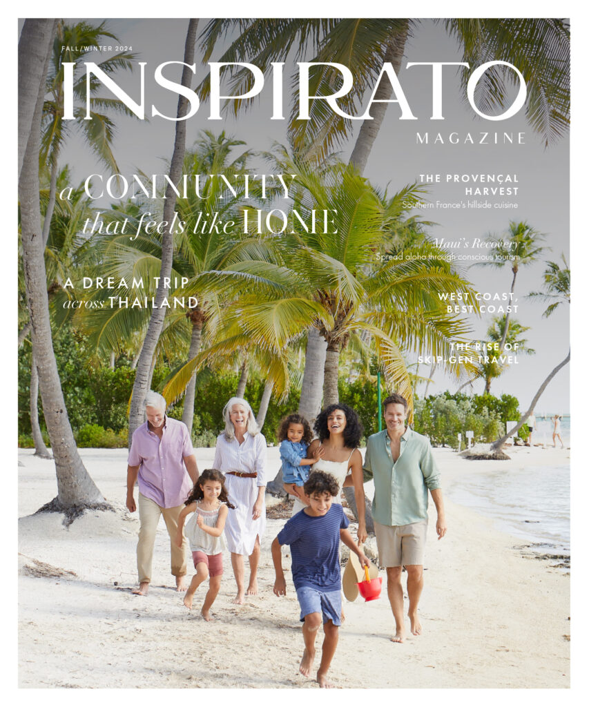 The cover of Inspirato's luxury travel magazine with a family walking along the beach under palm trees.