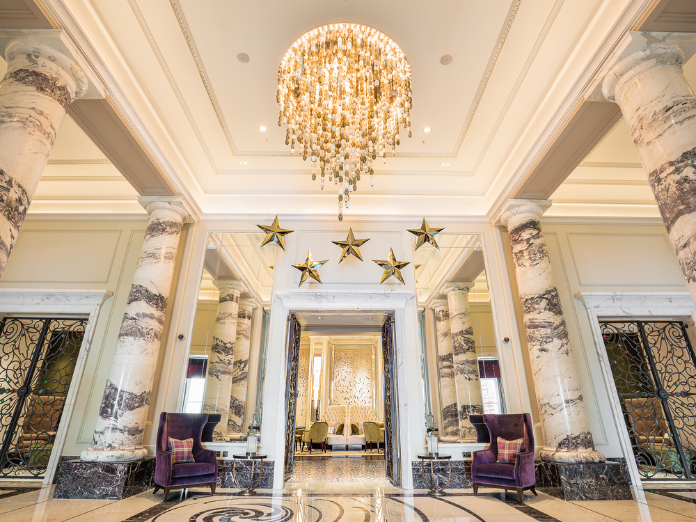 Langham lobby with large chandelier and marble pillars.