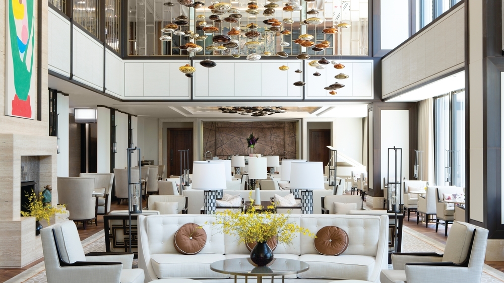 Lobby with white furniture arranged in sitting circles with abstract overhead lighting. 