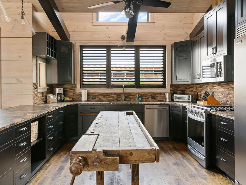 Salt Tide kitchen with black kitchen with raw wood kitchen island with stainless steel appliances throughout kitchen.